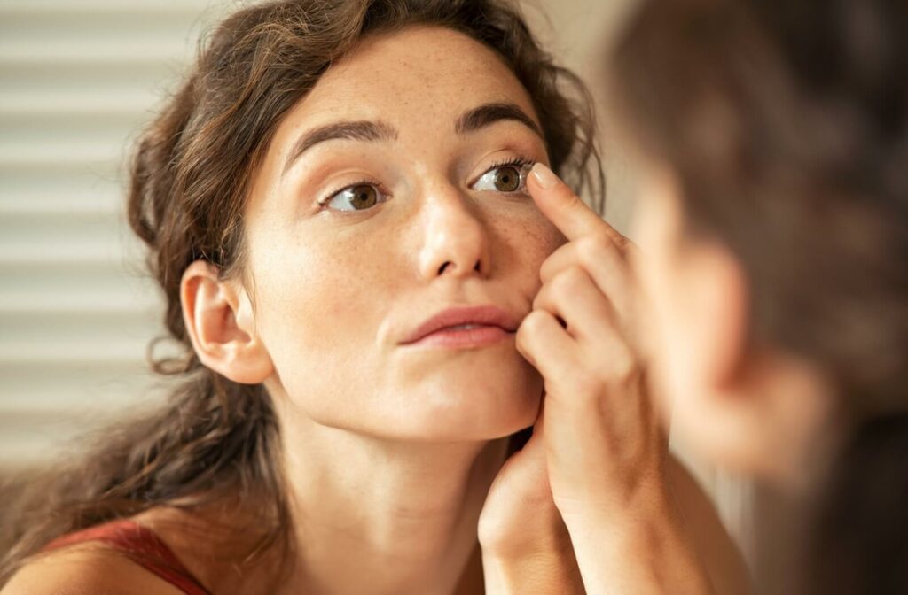 A young woman putting in scleral contact lenses to help with her dry eye syndrome.