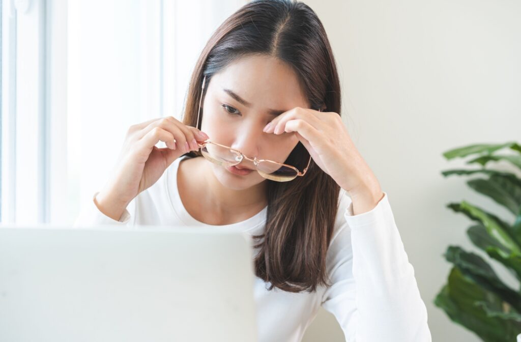  Young woman removing her glasses and rubbing her eyes due to discomfort, highlighting the need for IPL and RF treatments for dry eye relief.