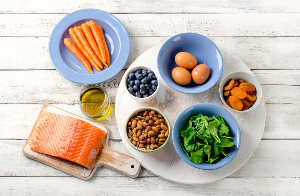 Different eye-healthy foods such as salmon and carrots laid out on a table