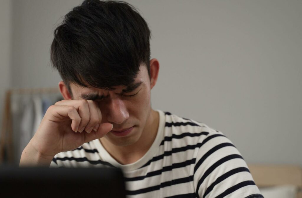 Man rubbing his eye in discomfort, illustrating eye pain when blinking