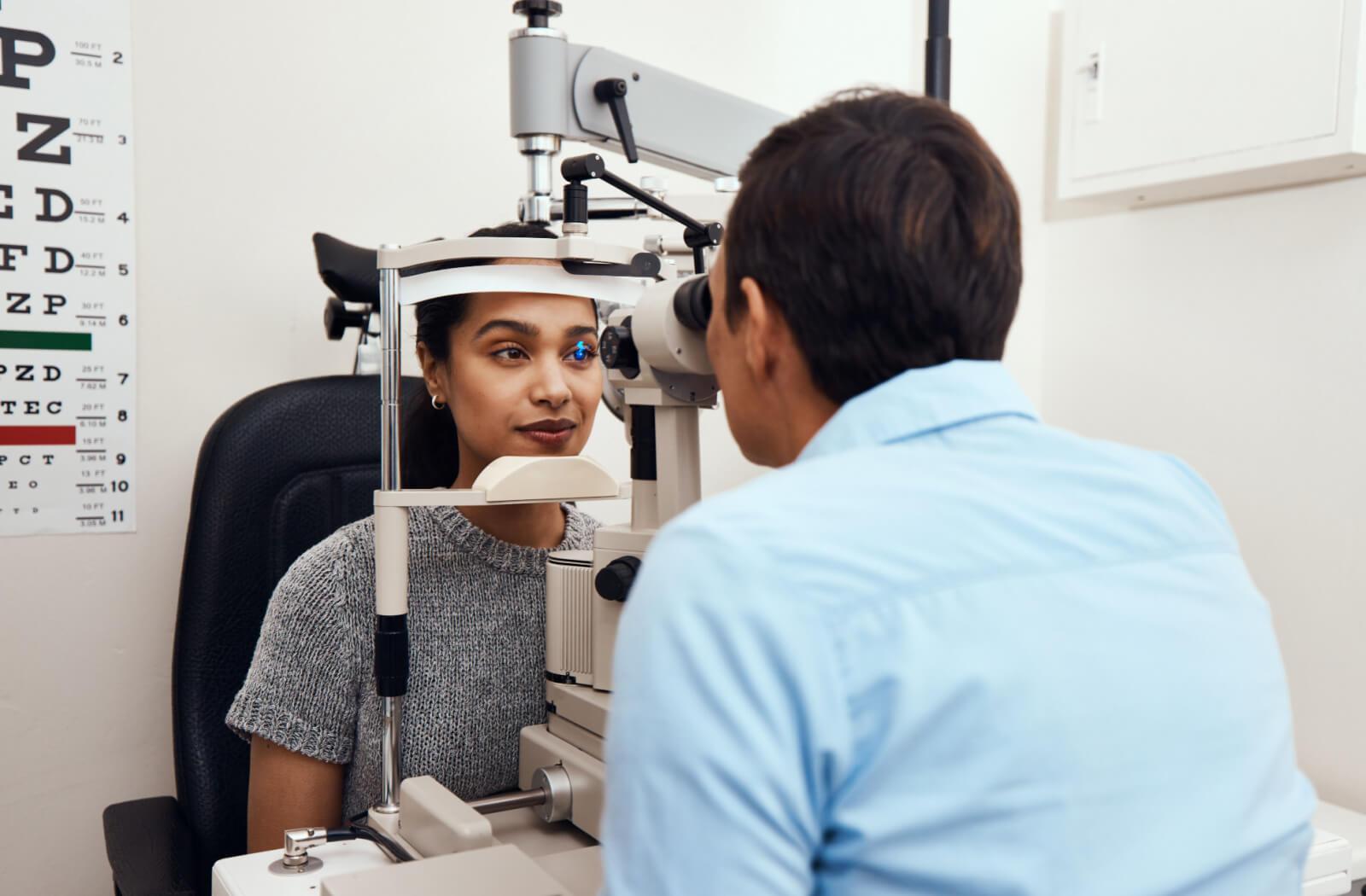Optometrist performing an eye exam with slit lamp to diagnose eye pain and irritation